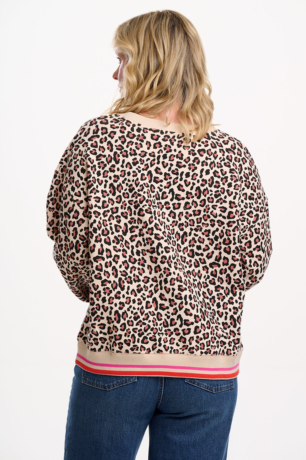 Sugarhill Brighton model wearing a leopard print top with blue jeans on a white background