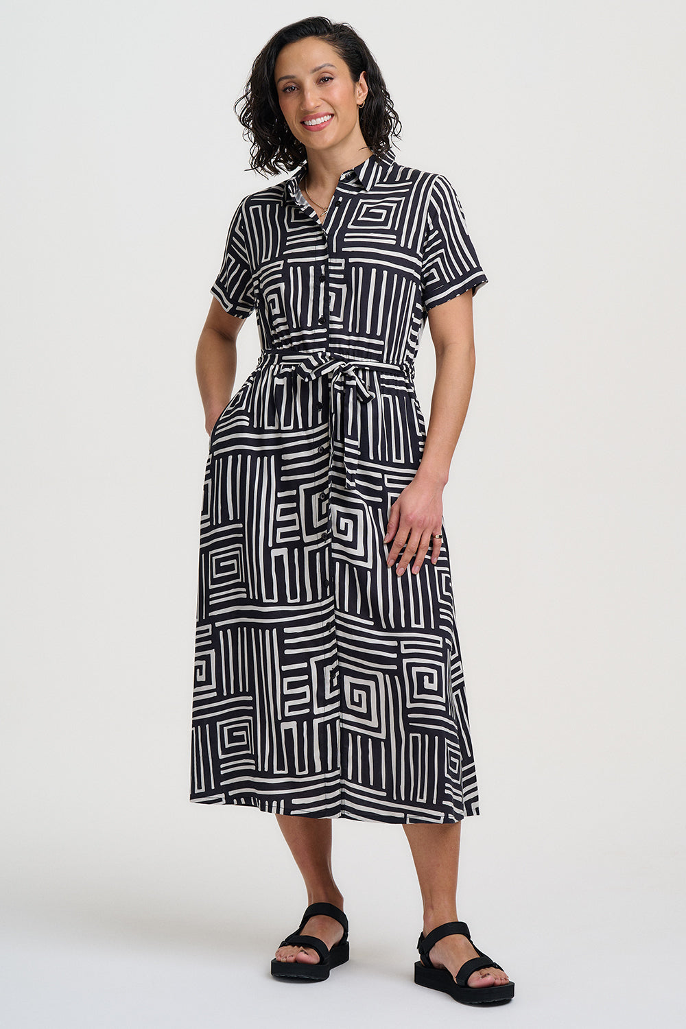 Woman wearing a black and white geometric patterned dress on a white background