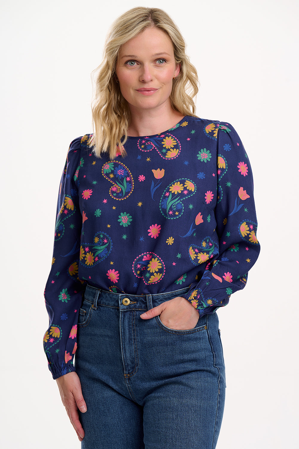 Sugarhill Brighton model wearing a navy blue blouse with colourful floral patterns on a white background