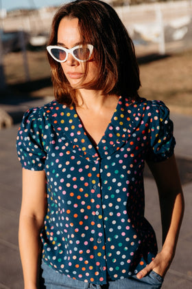 Woman wearing a colorful polka dot blouse and blue jeans 