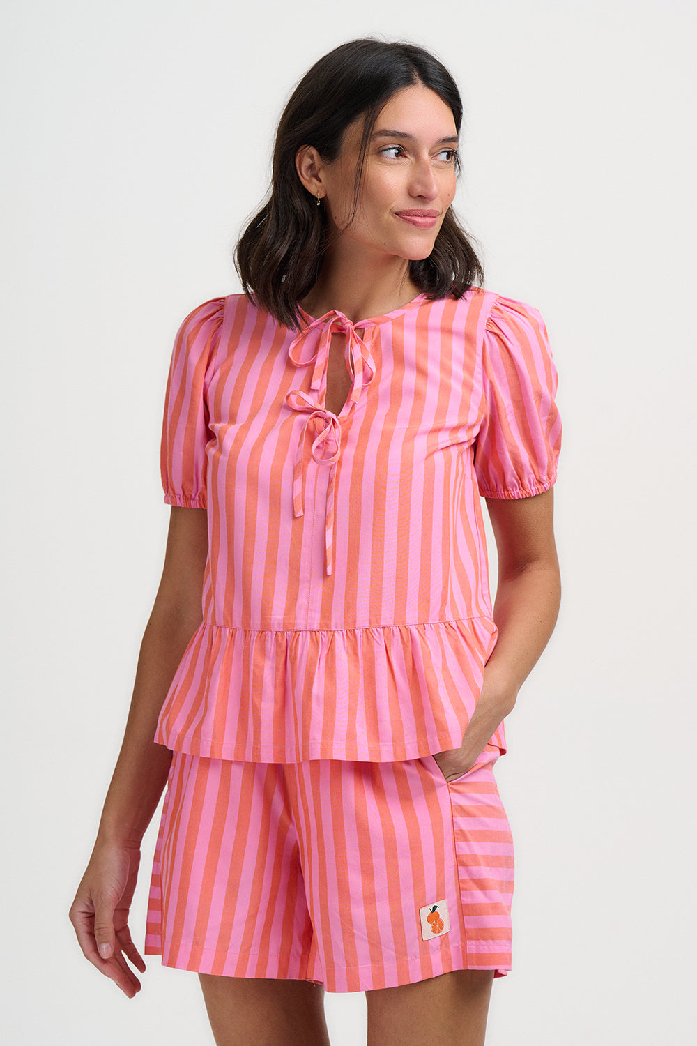 Woman wearing a pink and white striped outfit on a plain background