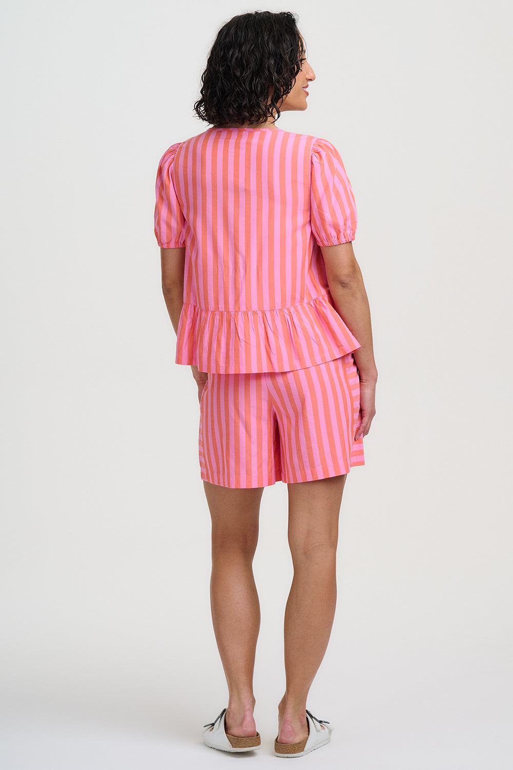 Person wearing a pink and white striped outfit on a white background