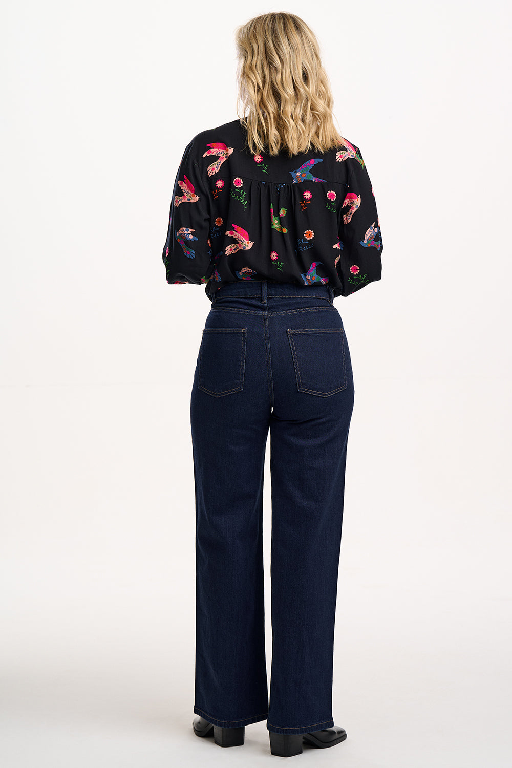 Suagrhill Brighton model wearing a black floral blouse and dark blue jeans on a white background
