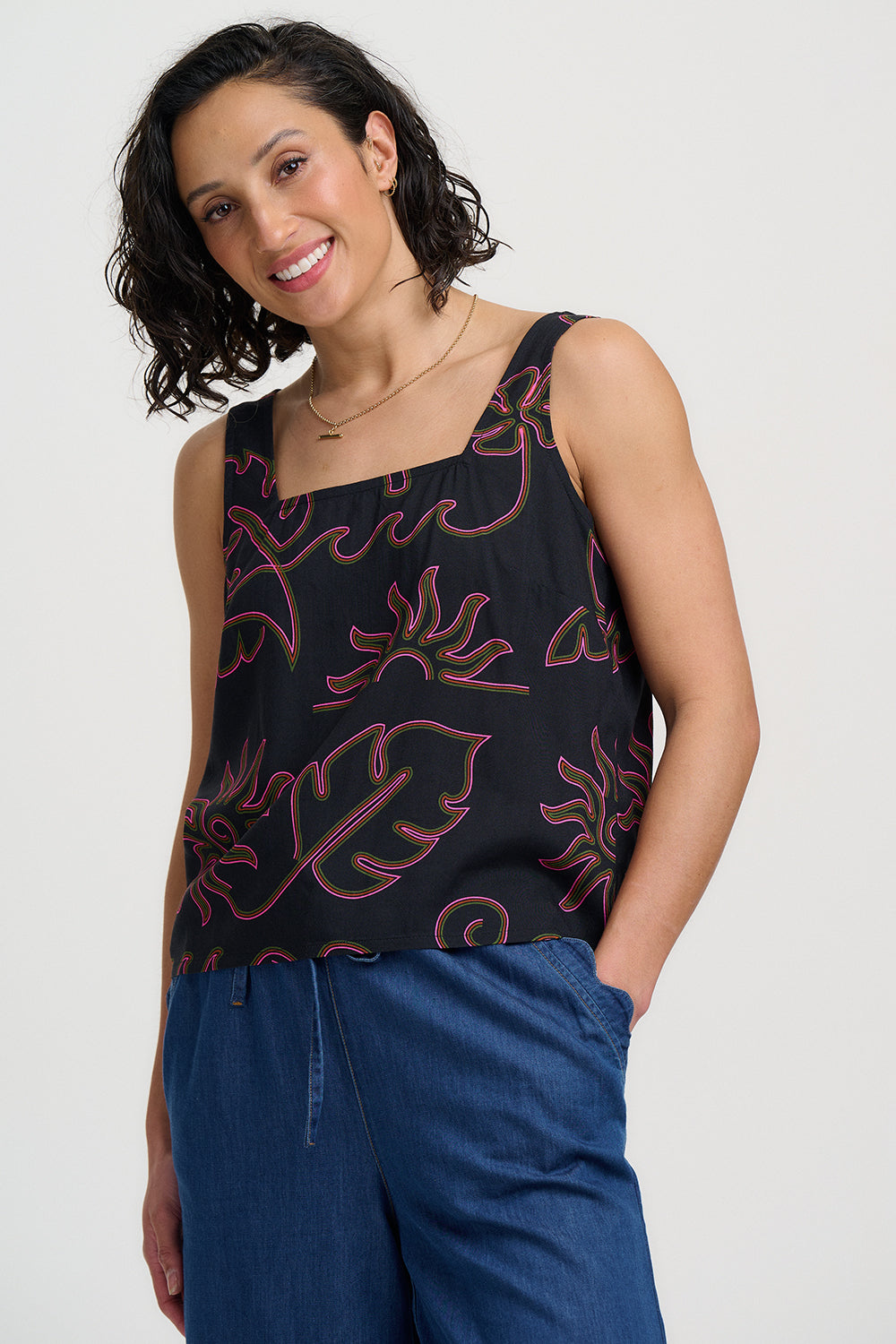 Woman wearing a black tank top with red floral patterns on a white background