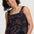 Woman wearing a black tank top with red floral patterns on a white background