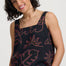 Woman wearing a black tank top with red floral patterns on a white background