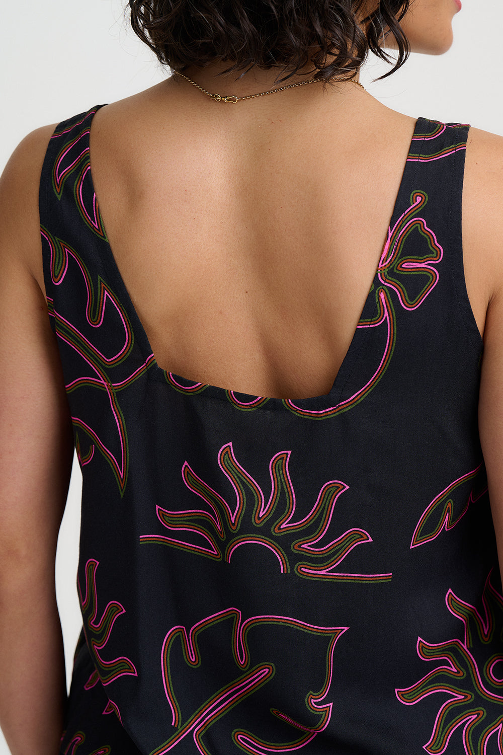 Black sleeveless top with pink floral patterns on a white background