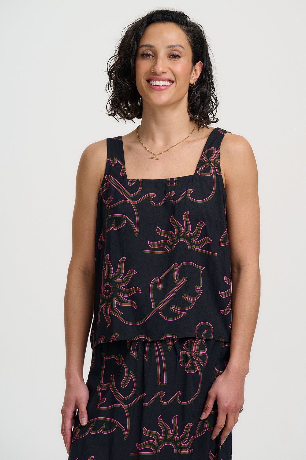 Woman wearing a black sleeveless top with pink floral patterns on a white background