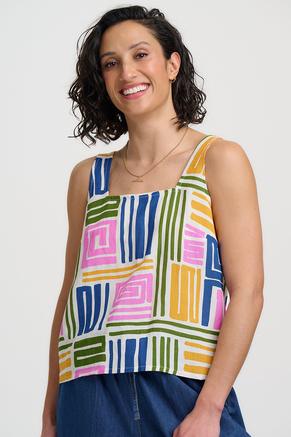 Woman wearing a colorful geometric-patterned sleeveless top against a plain background