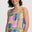 Woman wearing a colorful geometric-patterned sleeveless top against a plain background