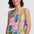 Woman wearing a colorful geometric-patterned sleeveless top against a plain background