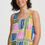 Woman wearing a colorful geometric-patterned sleeveless top against a plain background