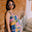 Woman in a colorful geometric dress standing against a brick wall.