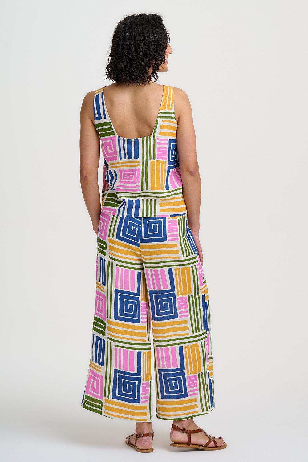 Woman wearing a colorful geometric patterned jumpsuit on a white background