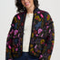 Woman wearing a colorful floral-patterned jacket on a white background