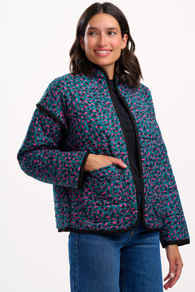Woman wearing a patterned jacket and jeans on a white background