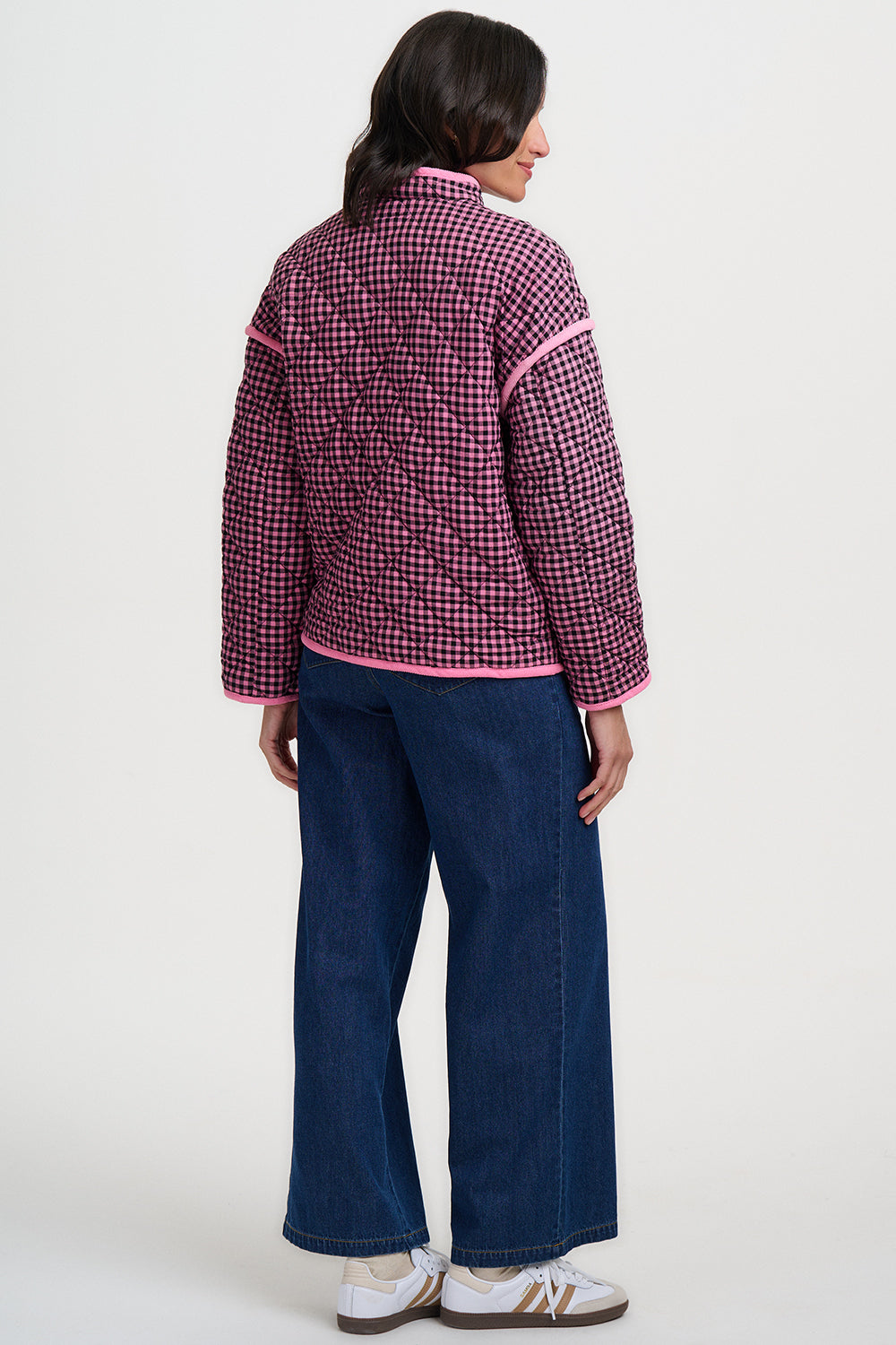 Person wearing a red and white checkered shirt with blue jeans on a white background