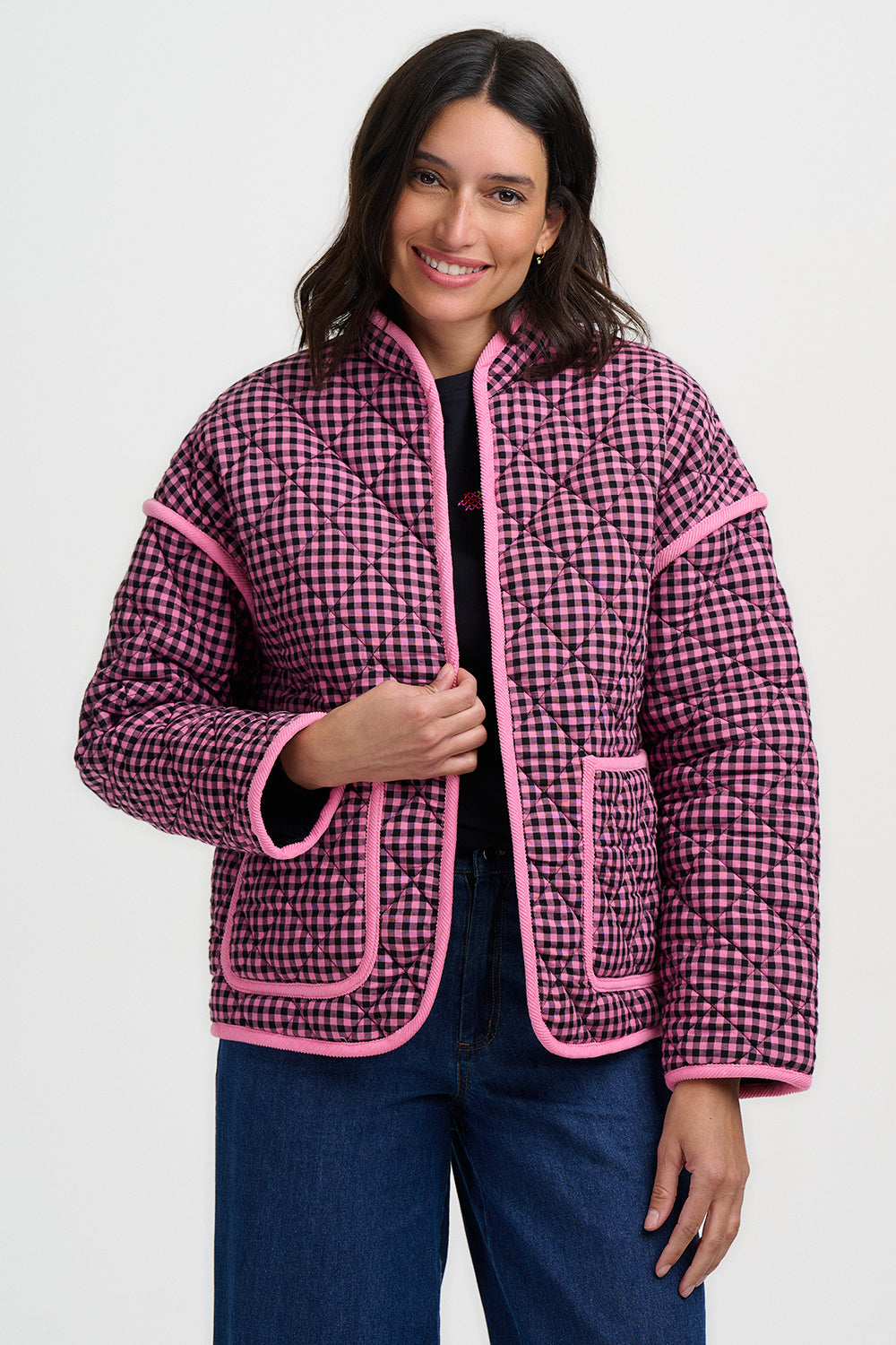 Woman wearing a pink and black checkered jacket with pink trim on a white background