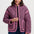 Woman wearing a pink and black checkered jacket with pink trim on a white background