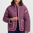 Woman wearing a pink and black checkered jacket with pink trim on a white background