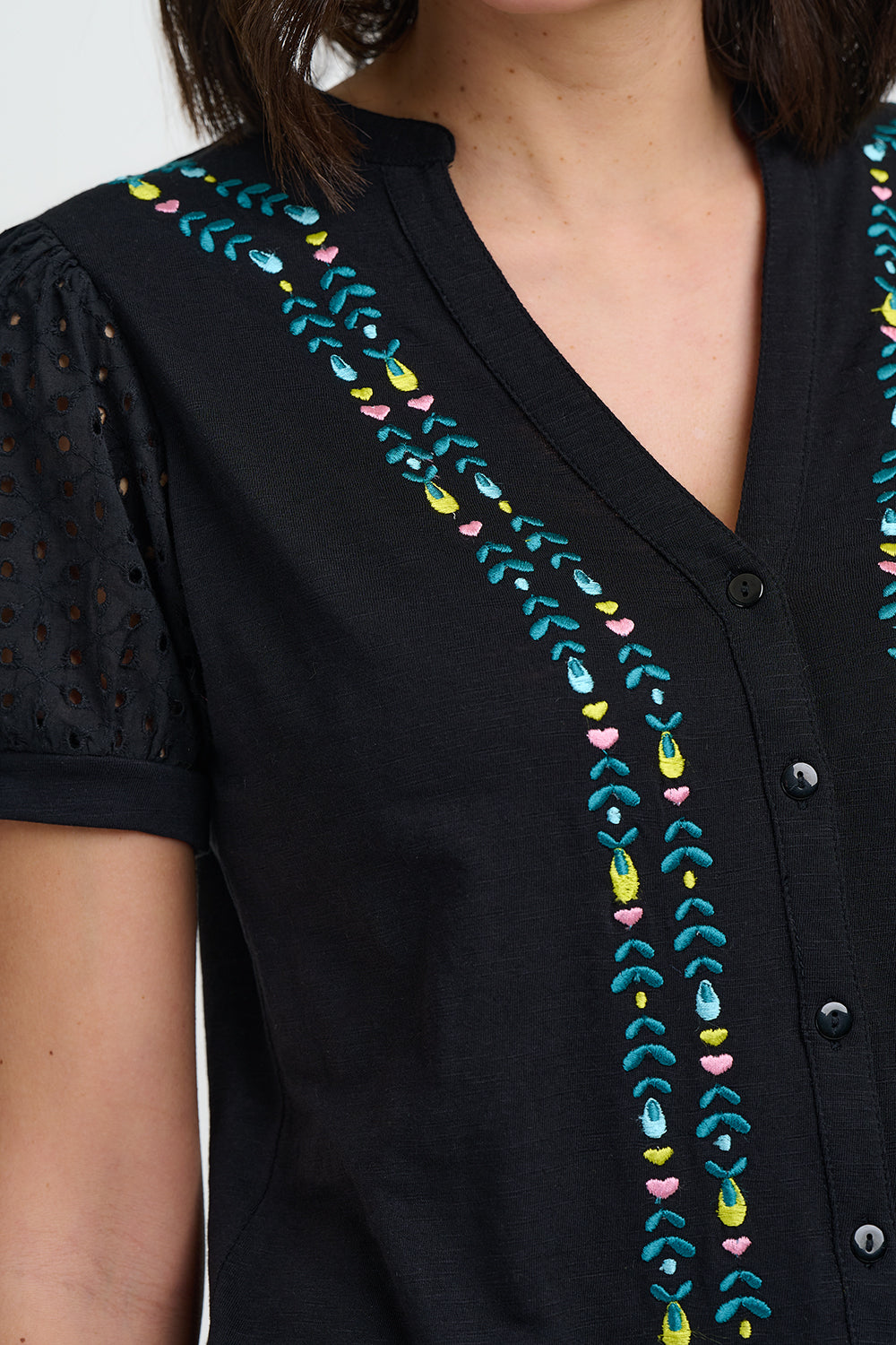 Black top with colorful embroidery on a plain background