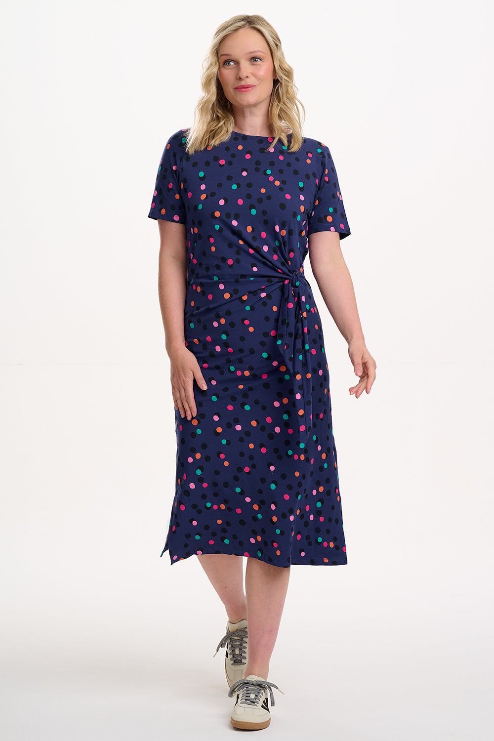 Woman wearing a navy dress with colorful polka dots on a white background