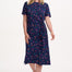 Woman wearing a navy dress with colorful polka dots on a white background