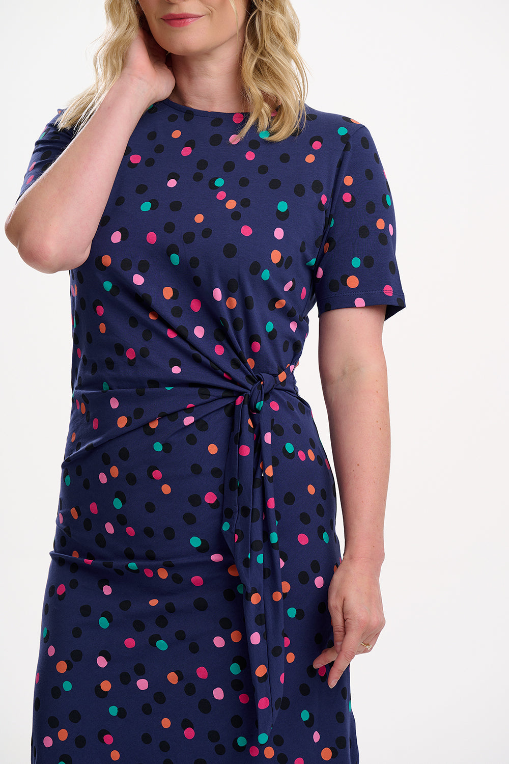 Woman wearing a navy dress with colorful polka dots on a white background
