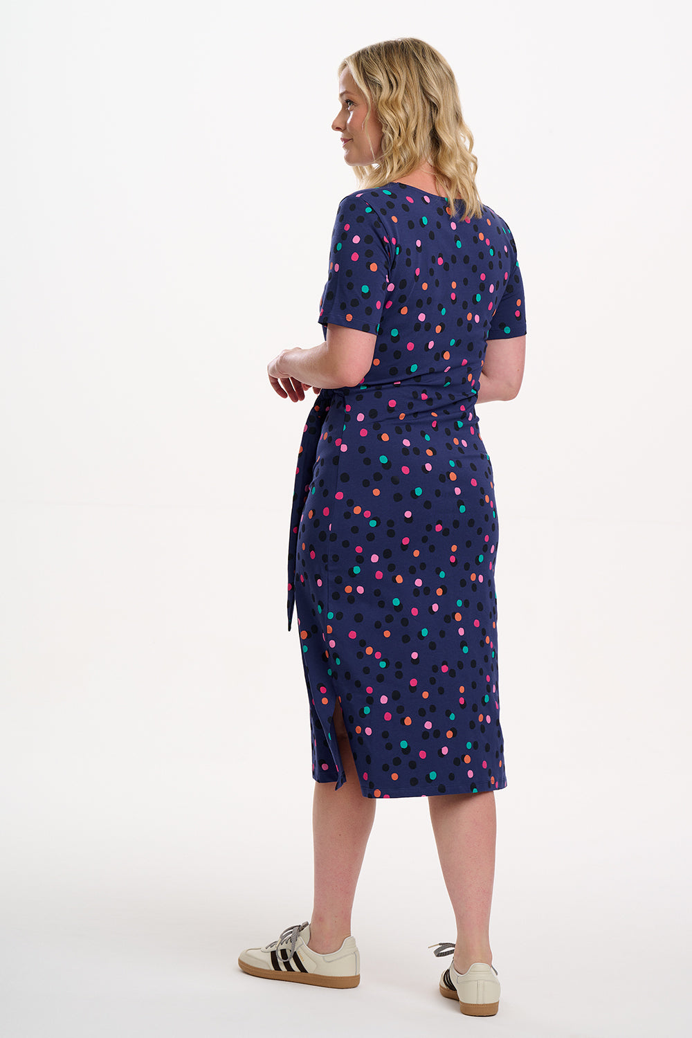 Woman wearing a navy dress with colorful polka dots on a white background