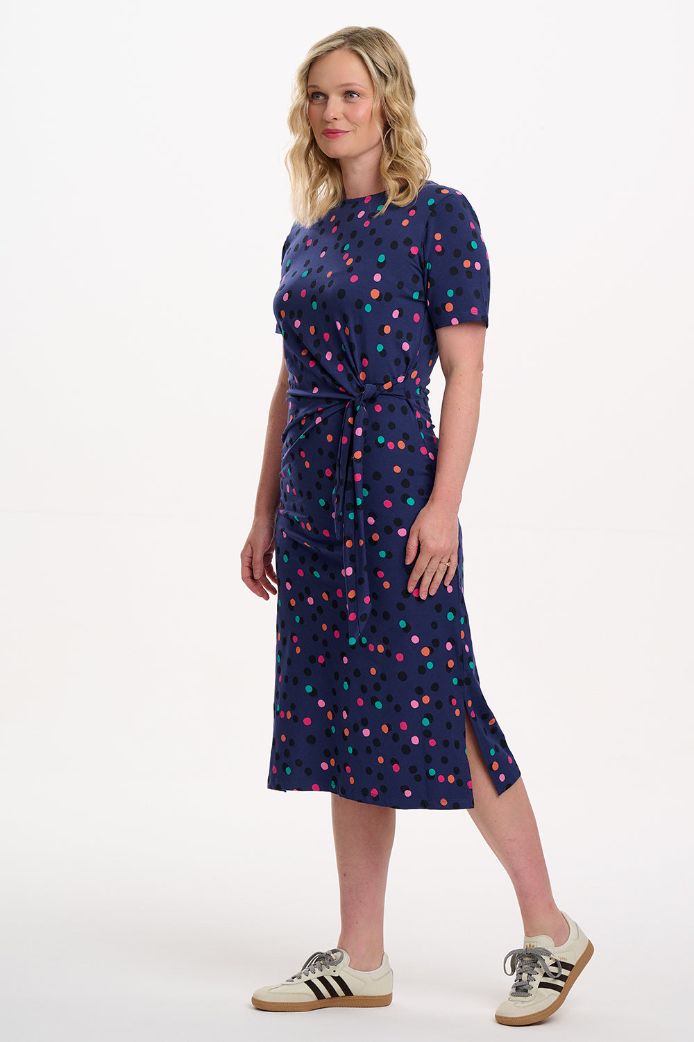 Woman wearing a navy dress with colorful polka dots on a white background