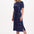 Woman wearing a navy dress with colorful polka dots on a white background