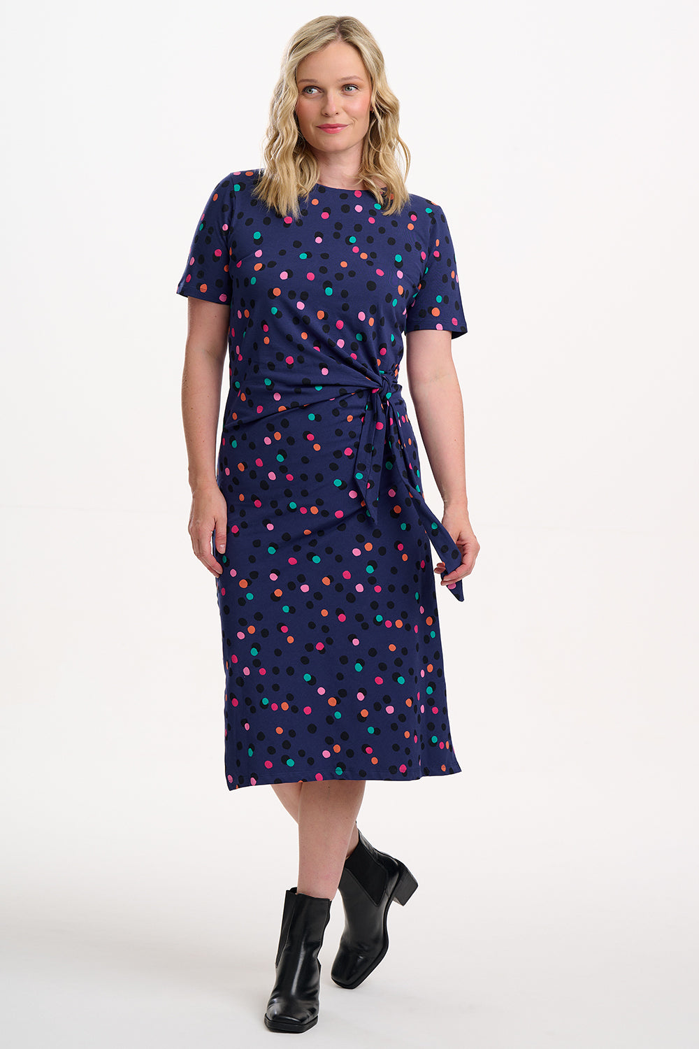 Woman wearing a navy dress with colorful polka dots on a white background