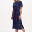 Woman wearing a navy dress with colorful polka dots on a white background