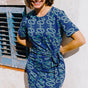 A woman smiling and posing in a bright navy midi dress with a geometric star snakes print.