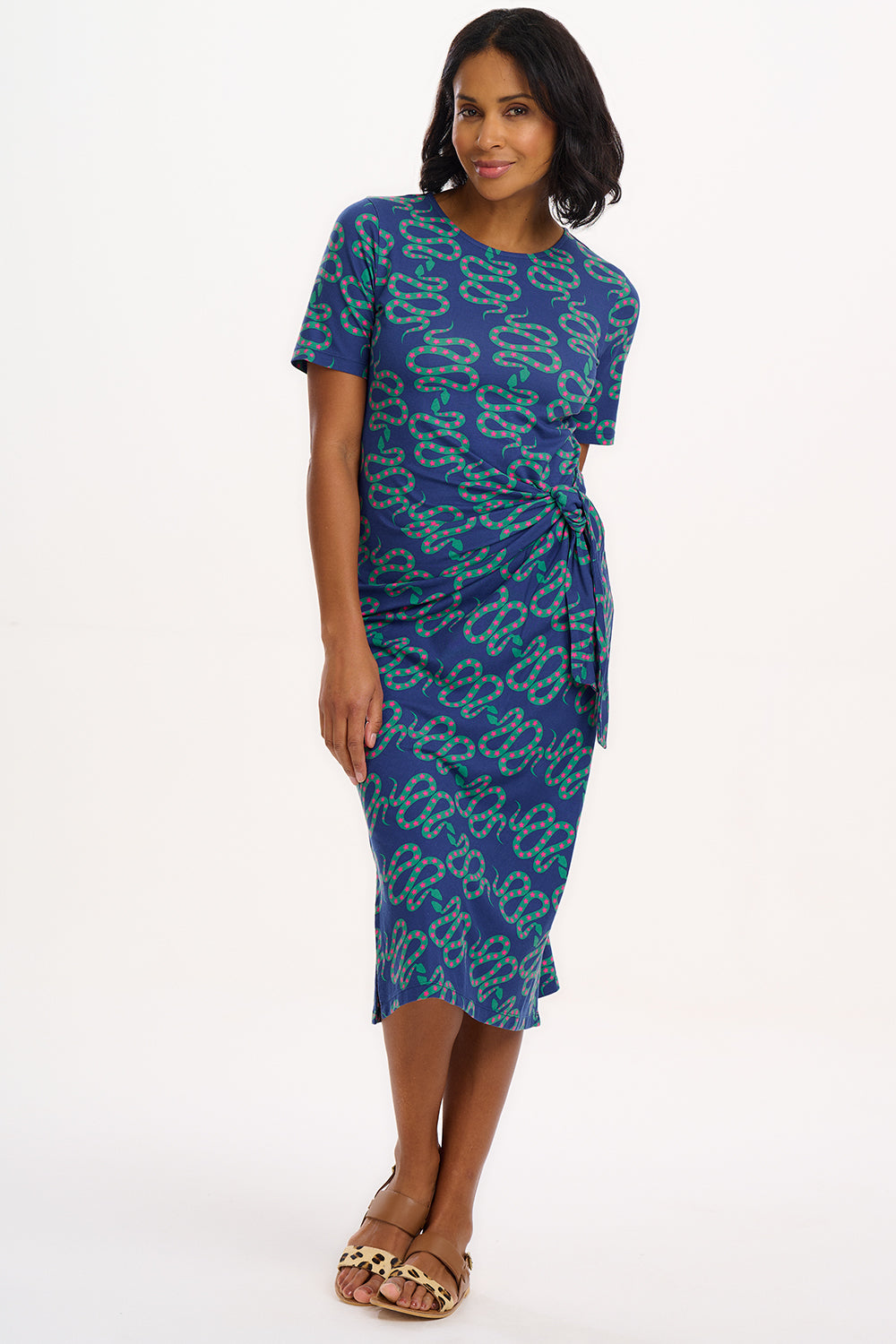 A model wearing a bright navy blue jersey midi dress with a star and snake pattern, featuring short sleeves and a waist tie.