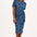 A model wearing a bright navy blue jersey midi dress with a star and snake pattern, featuring short sleeves and a waist tie.