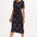 A woman wearing a midi jersey dress with a giraffe print in multiple colors on a black base.