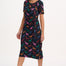 A woman wearing a midi jersey dress with a giraffe print in multiple colors on a black base.