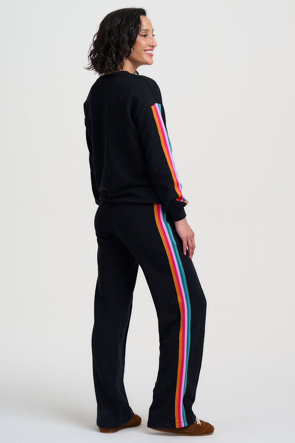 Person wearing a black outfit with colorful stripes on a white background