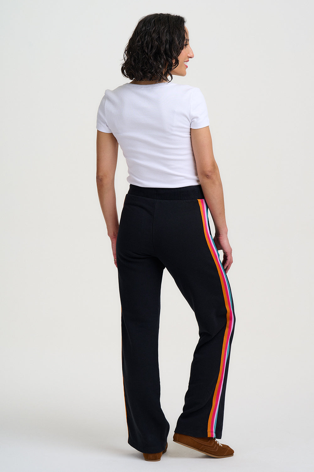 Person wearing black pants with colorful stripes on a white background