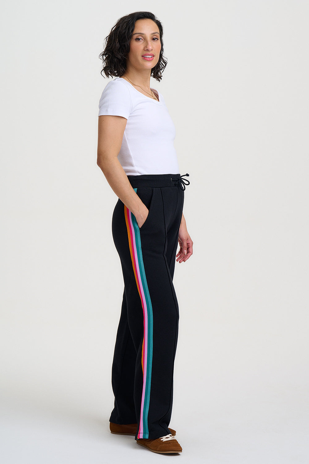 Woman wearing black pants with colorful stripes on a white background