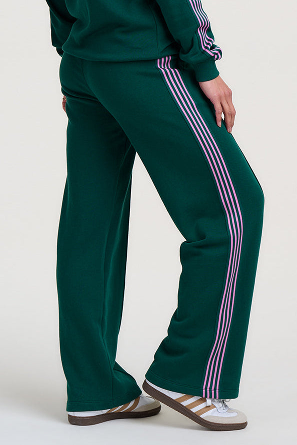 Person wearing a green tracksuit with pink stripes on a white background