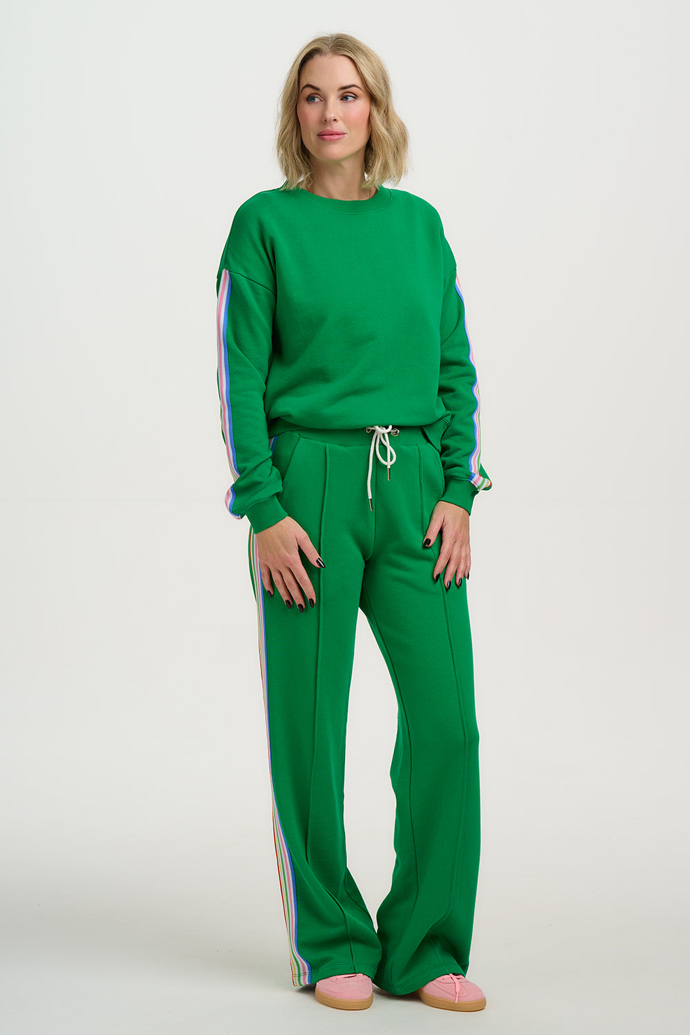 Woman wearing a green tracksuit with colorful accents on a white background