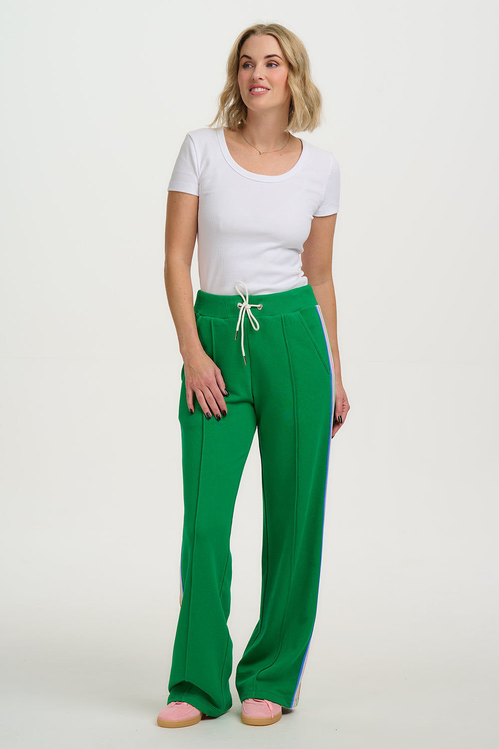 Woman wearing a white top and green pants on a white background