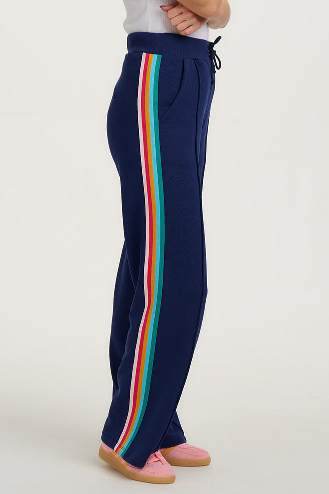 Woman wearing navy sweatpants with colorful stripes on a white background