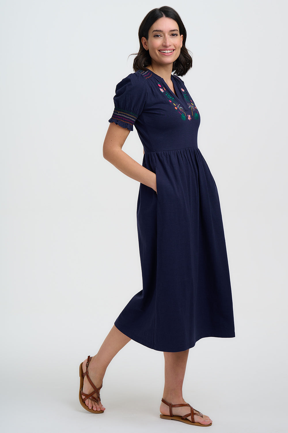 Woman wearing a navy dress with floral embroidery on a white background