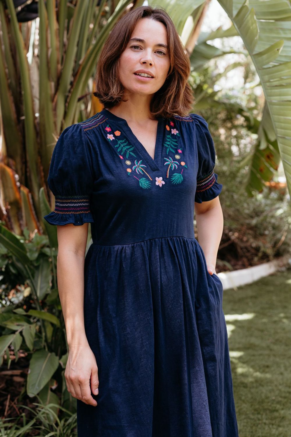 Woman wearing a navy blue dress with floral embroidery in an outdoor setting