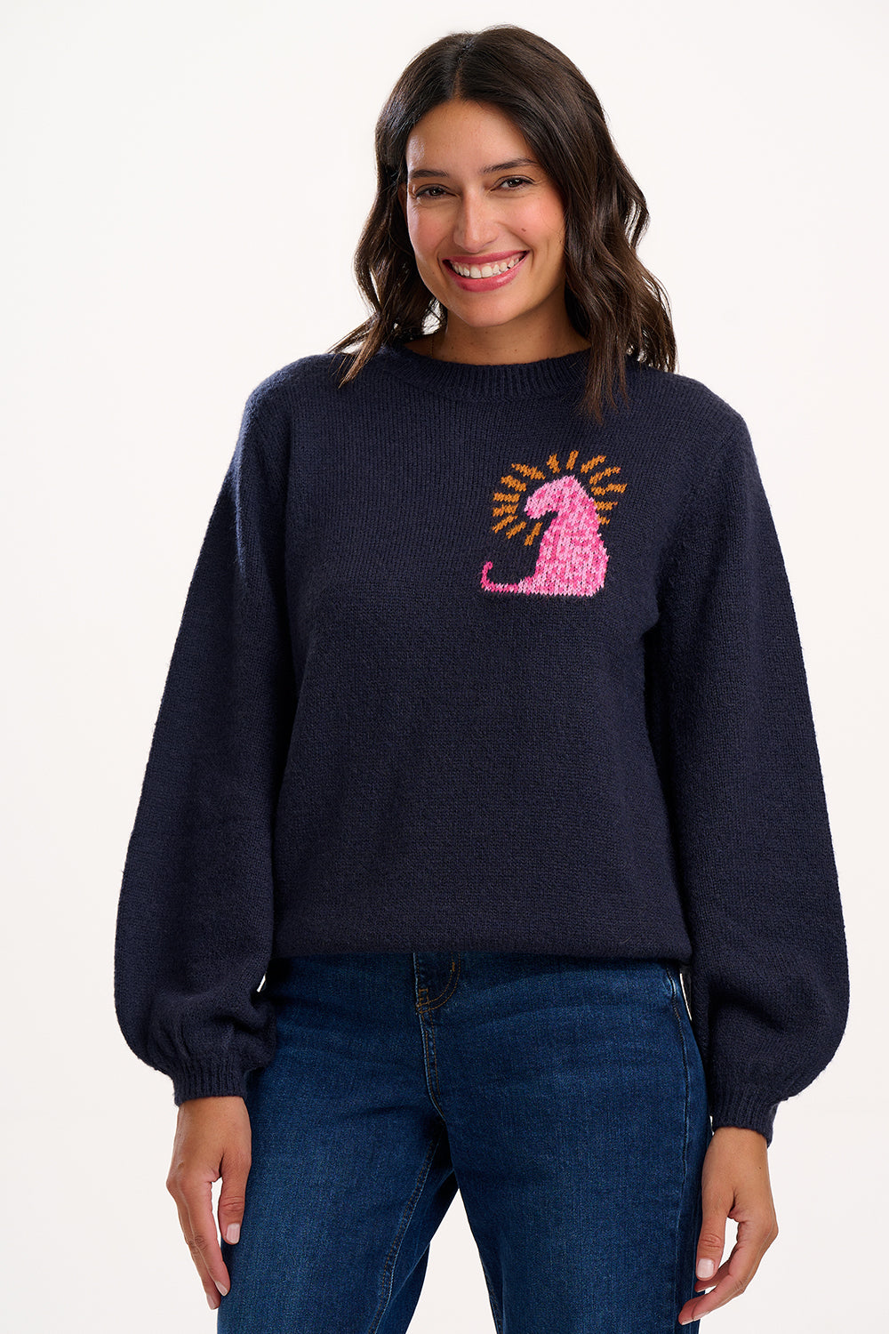 Woman wearing a navy sweater with a pink and yellow design on a white background