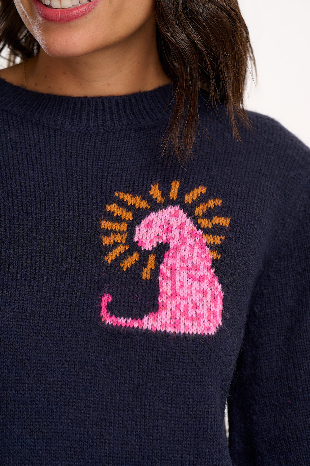 Navy blue sweater with a pink and orange cat design on a white background