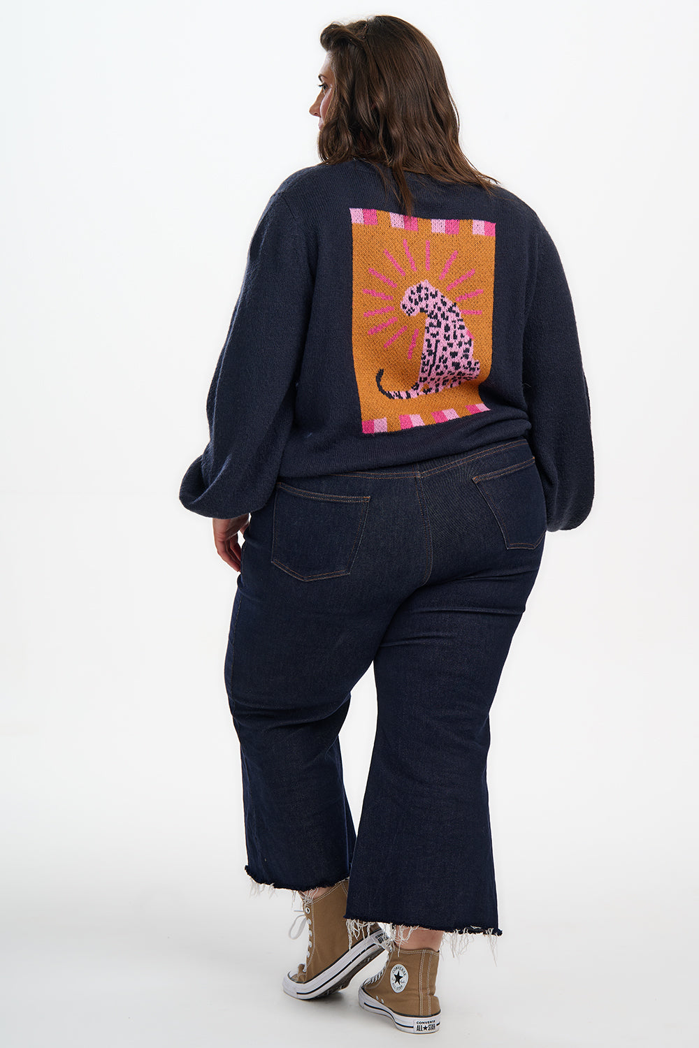 Person wearing a dark blue outfit with a colorful leopard design on the back, standing against a white background.